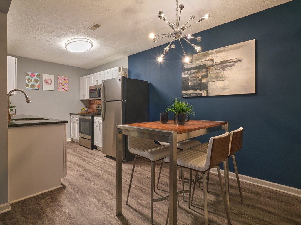 a dining area with a table and chairs and a kitchen with a refrigerator