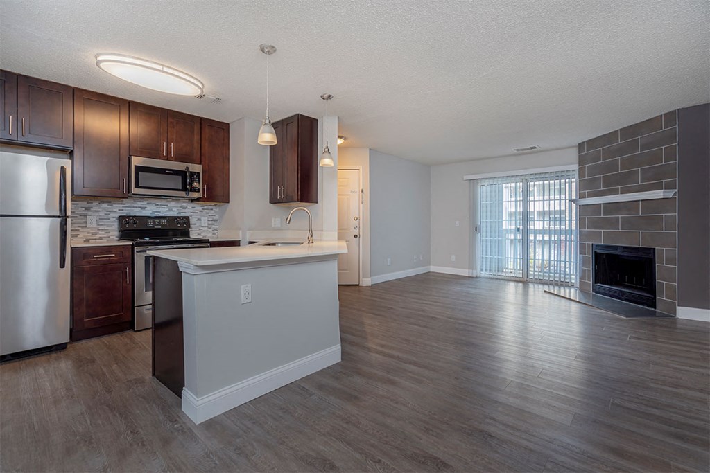 an empty kitchen and living room with wood flooring and a fireplace