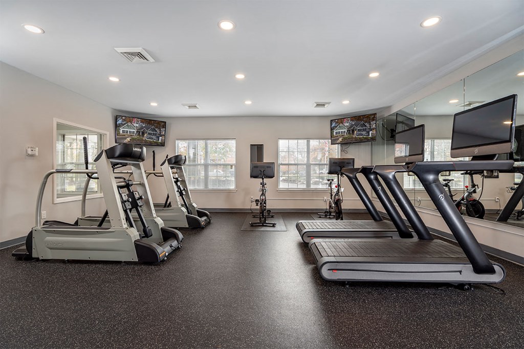 a gym with treadmills and weights and a tv