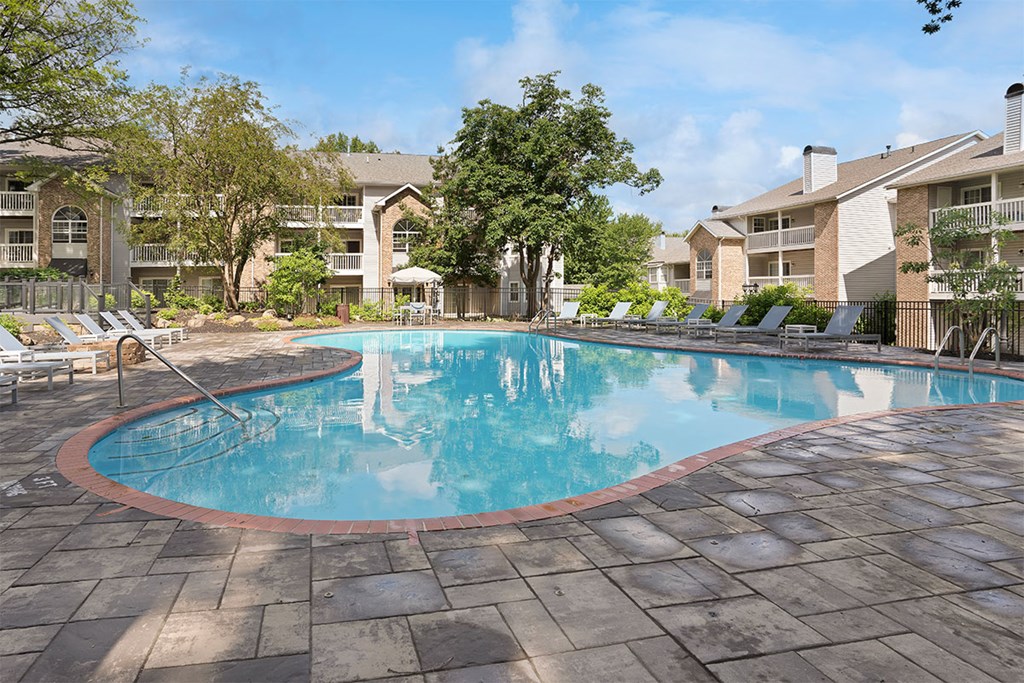 a resort style swimming pool with chaise lounge chairs and apartment buildings
