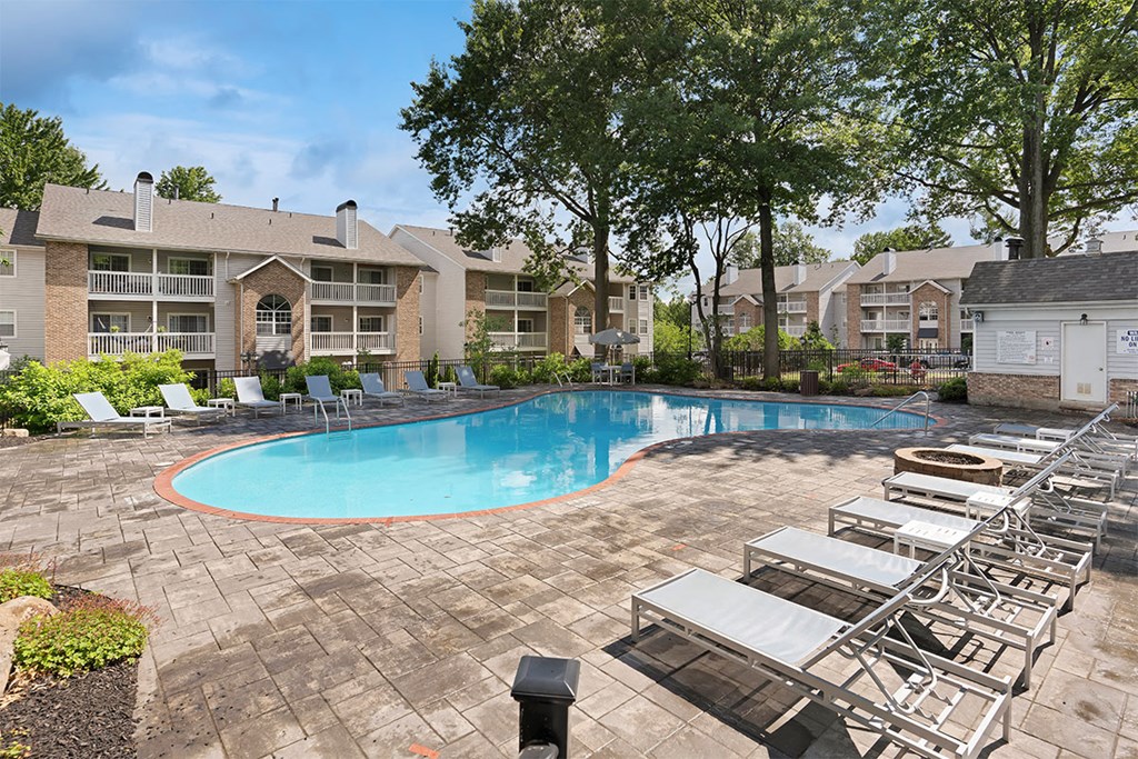 a resort style pool with lounge chairs and apartments in the background