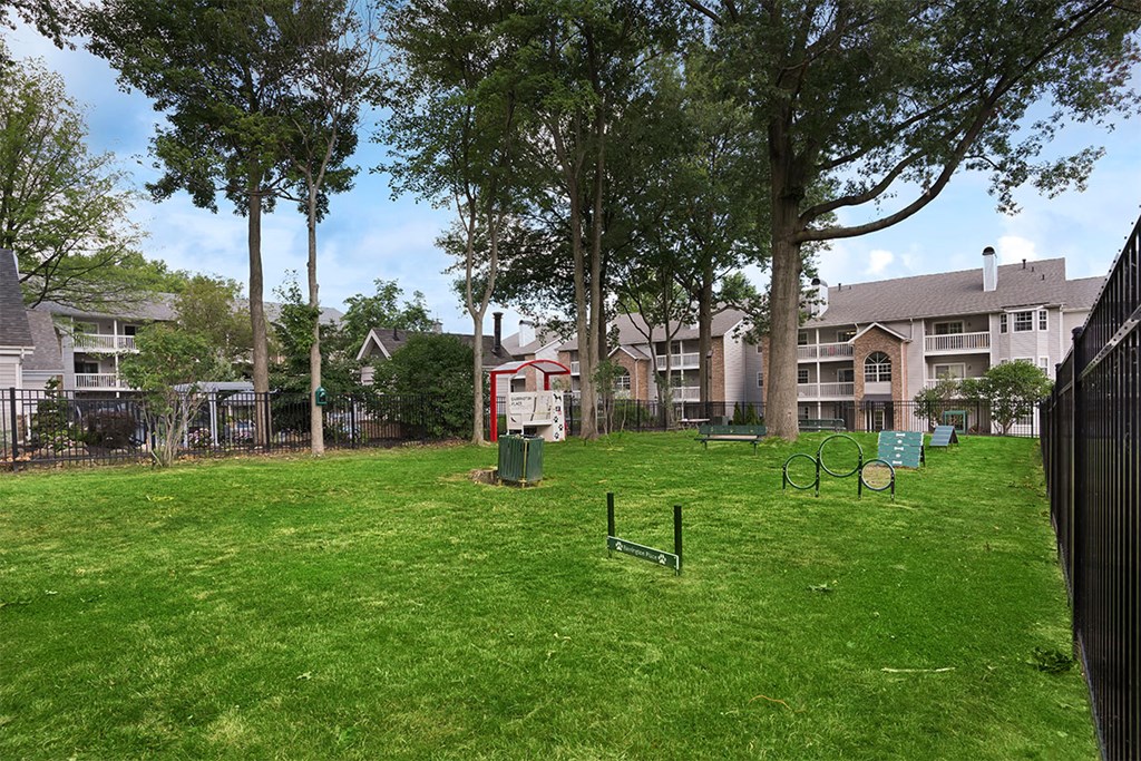 a yard with a playground and trees with apartments in the background