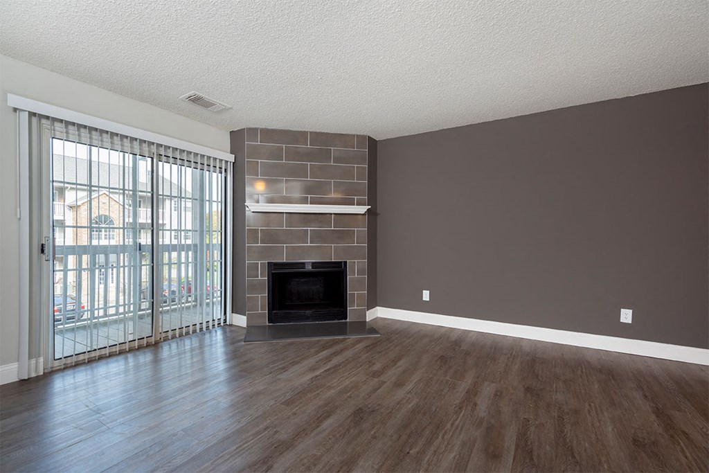 an empty living room with a fireplace and a sliding glass door