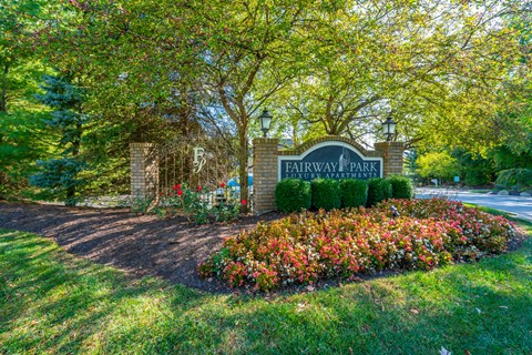 a sign for fairway park in front of trees and flowers