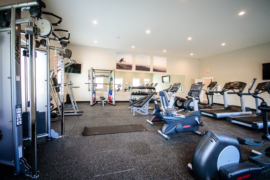a gym with cardio equipment and weights on the floor