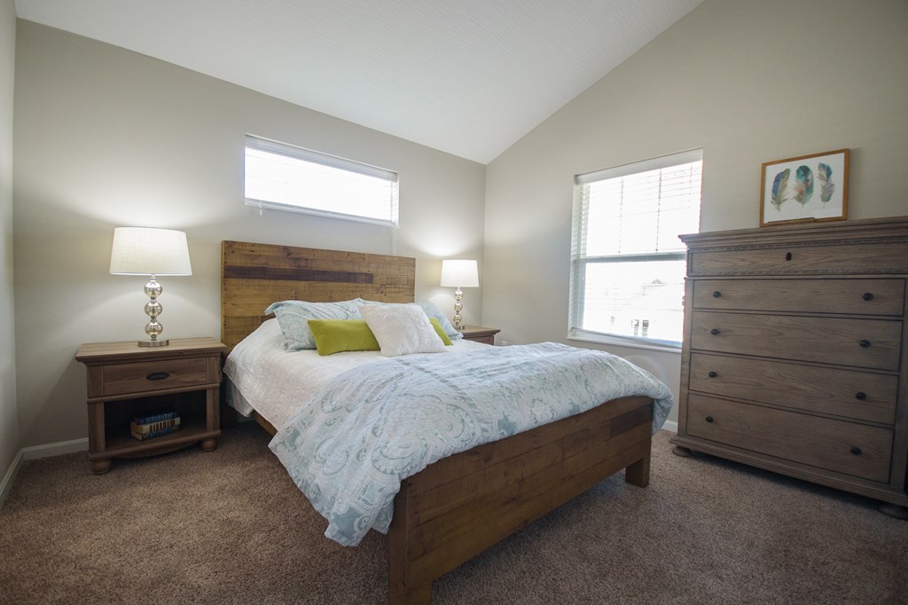 a bedroom with a bed and two dressers and a window