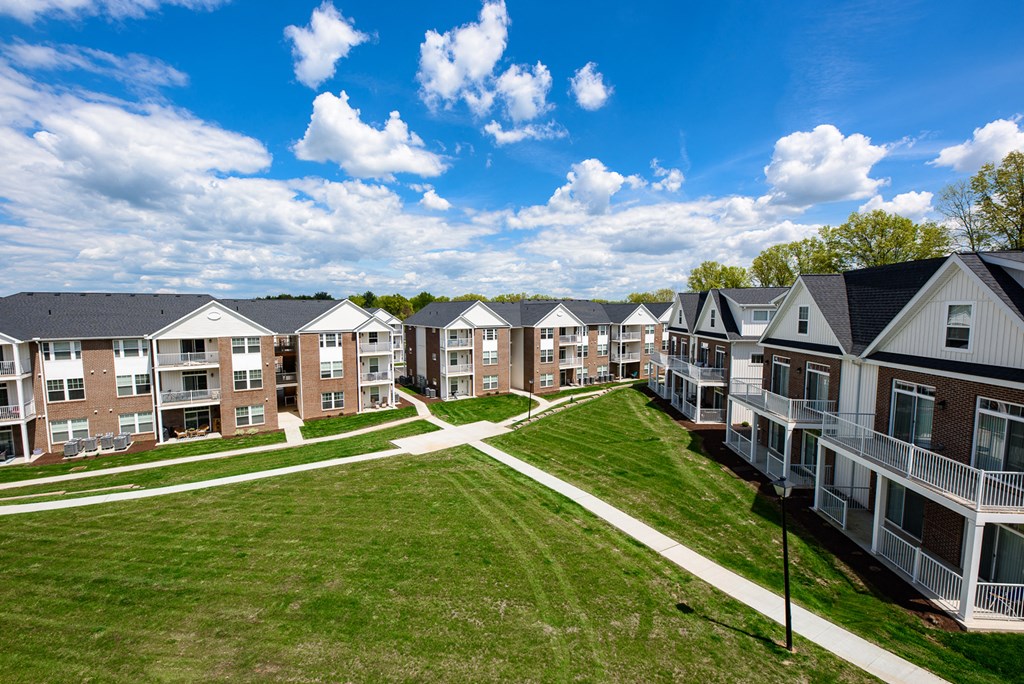 an aerial view of an apartment complex with green grass and a blue sky
