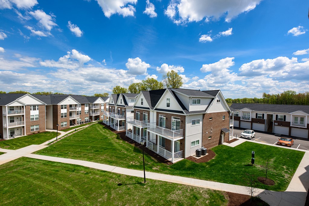 an aerial view of an apartment complex with green grass and a blue sky