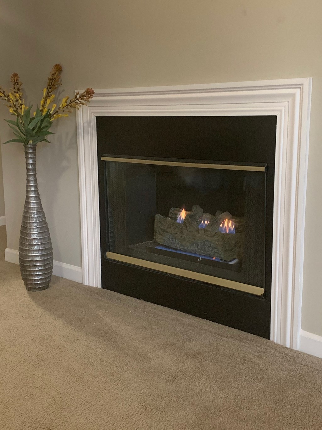 a fireplace in a living room with a vase of flowers