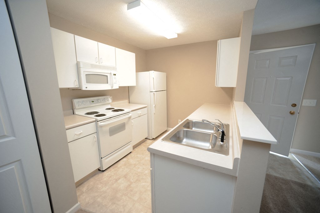 a kitchen with white appliances and white cabinets and a sink