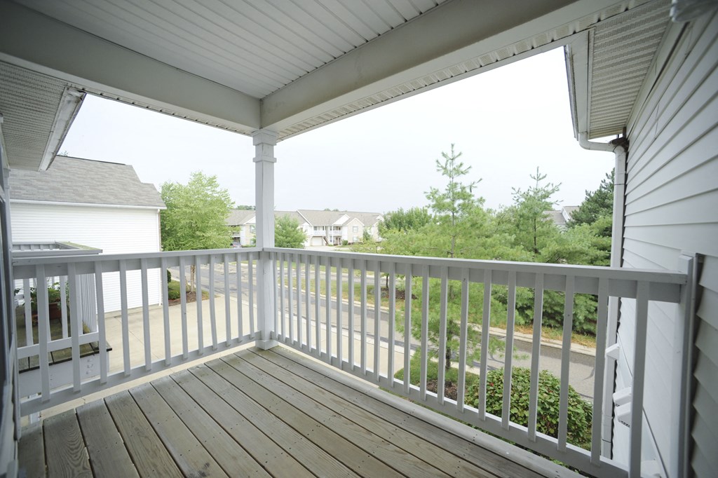 the view from the porch of a white house with a wooden deck