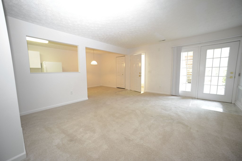 the living room and dining room of an empty home with white walls and carpet