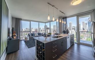 One bedroom kitchen with built-in wine rack, stainless steel appliances, cherry cabinets and hardwood flooring with floor to ceiling wrap around windows in the living room