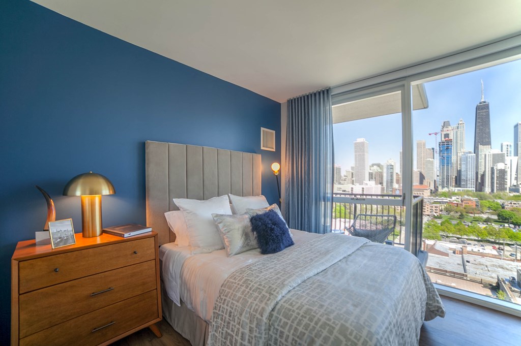 Second bedroom in the two bedroom layout that has a queen sized bed, night stand and floor to ceiling windows