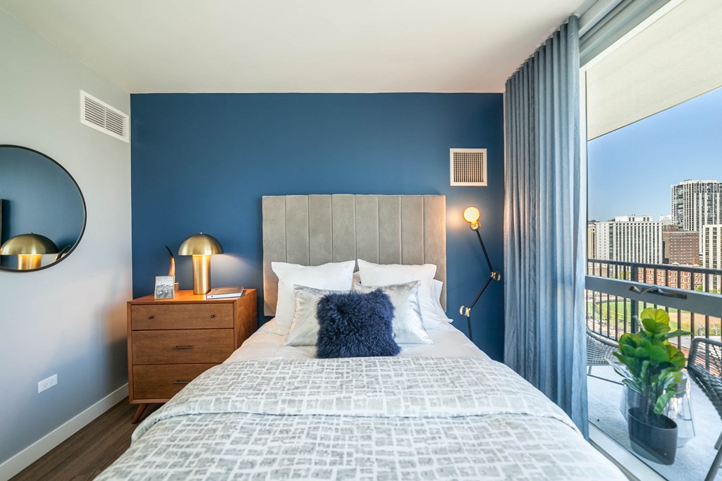 Second bedroom in the two bedroom layout that has a queen sized bed, night stand and floor to ceiling windows