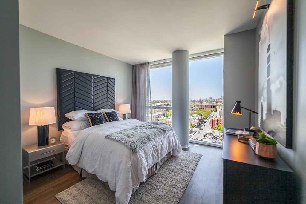 Two bedroom with queen sized bed, night stands, and dresser with floor to ceiling windows