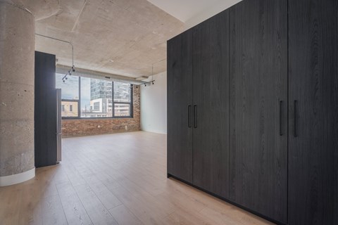 A room with black cupboards and wooden floors.
