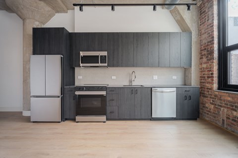 A kitchen with a white fridge, black cabinets, a white oven, a white dishwasher, and a white microwave.