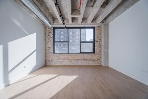 A room with wooden floors and a window with a view of a building outside.