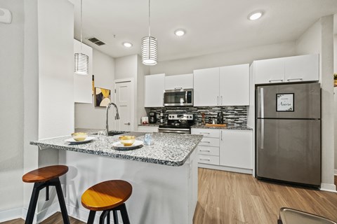 A kitchen with a granite countertop and a stainless steel refrigerator.