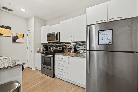 A modern kitchen with a stainless steel refrigerator and white cabinets.