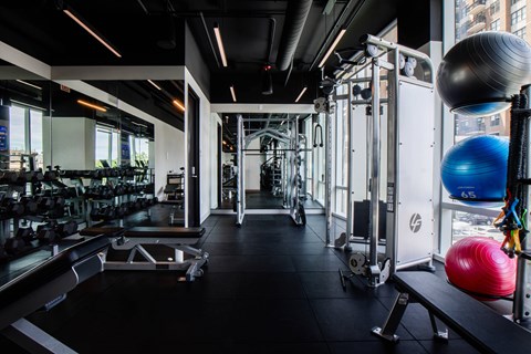 A gym with a variety of equipment including weights and exercise balls.