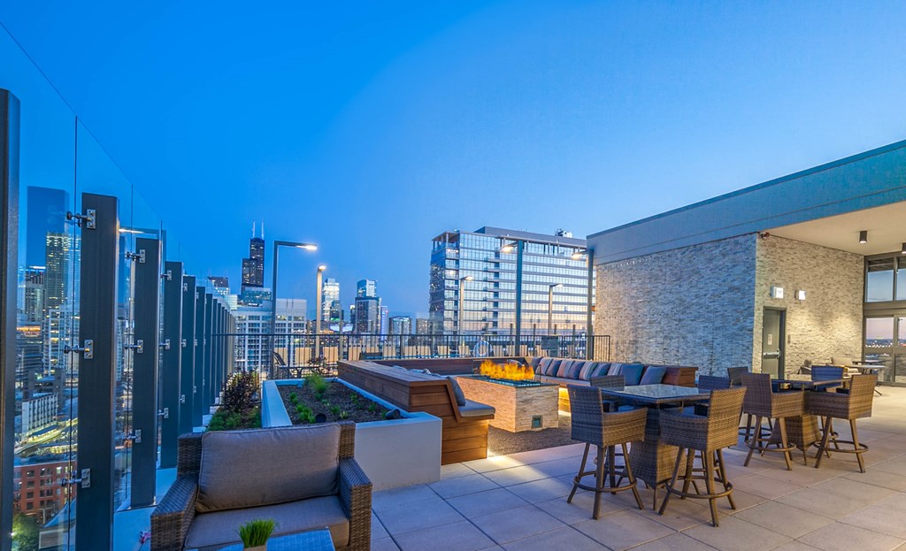 a rooftop terrace with tables and chairs and a city in the background