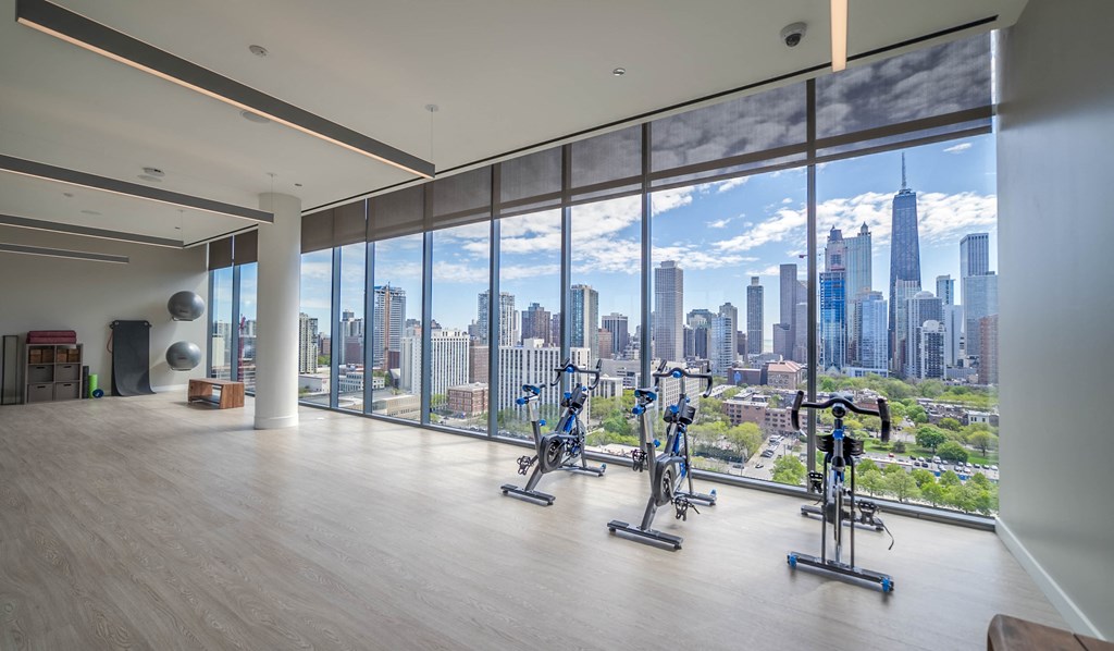 a fitness room with a view of the city skyline