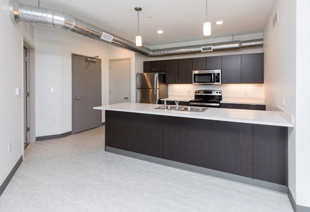an empty kitchen with an island and a stainless steel refrigerator