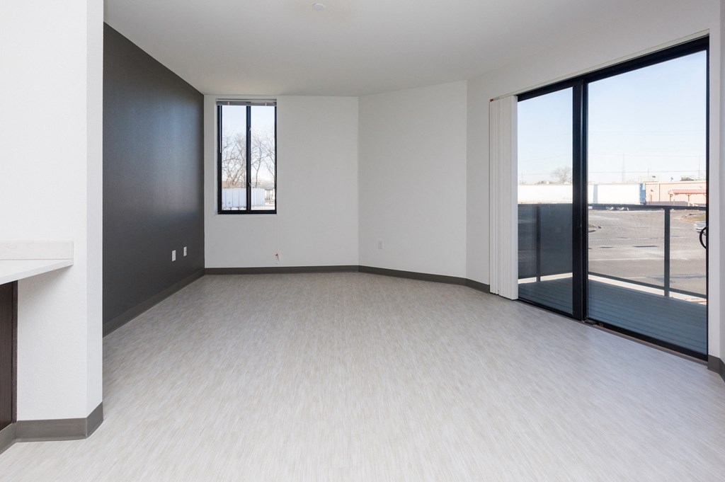 an empty living room with large windows and white flooring