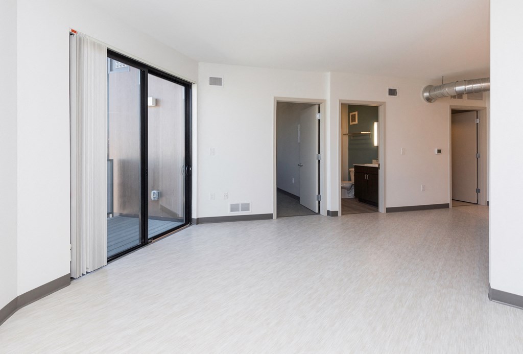 an empty living room with sliding glass doors and a white tile floor