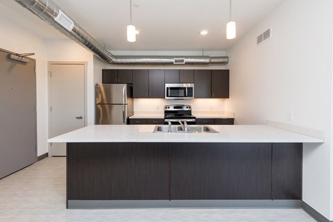 a kitchen with a white counter top and a stainless steel refrigerator