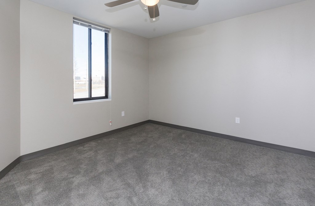 an empty living room with a ceiling fan and a window