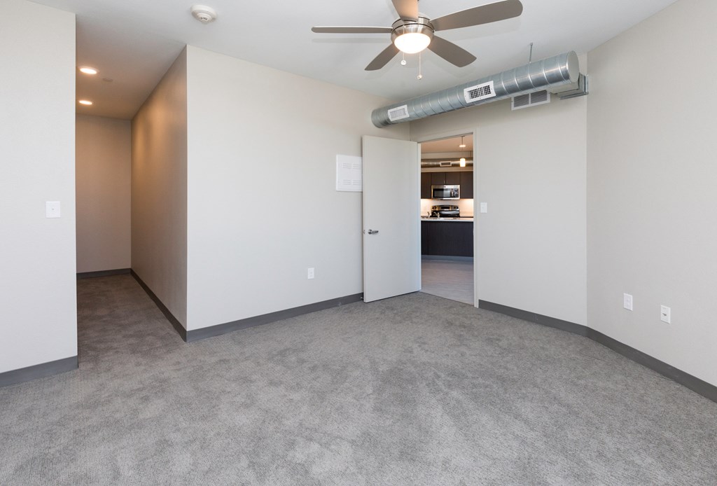 an empty living room with a ceiling fan and white walls