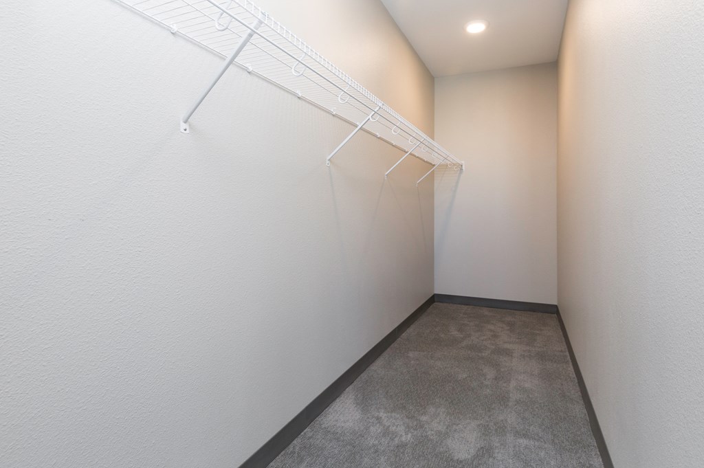 room with white walls and a white closet with three white racks