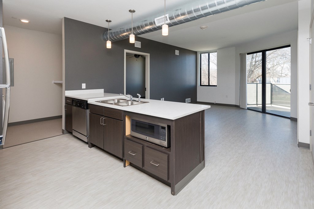 an empty kitchen with an island and a microwave in a building