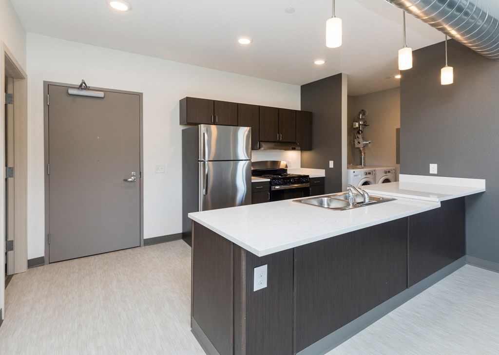 a kitchen with an island and a stainless steel refrigerator