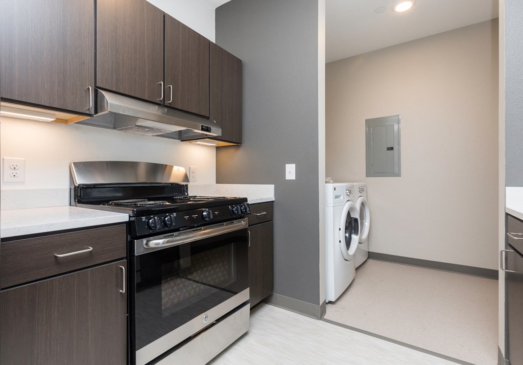 a kitchen with a stove and a washer and dryer and a laundry room