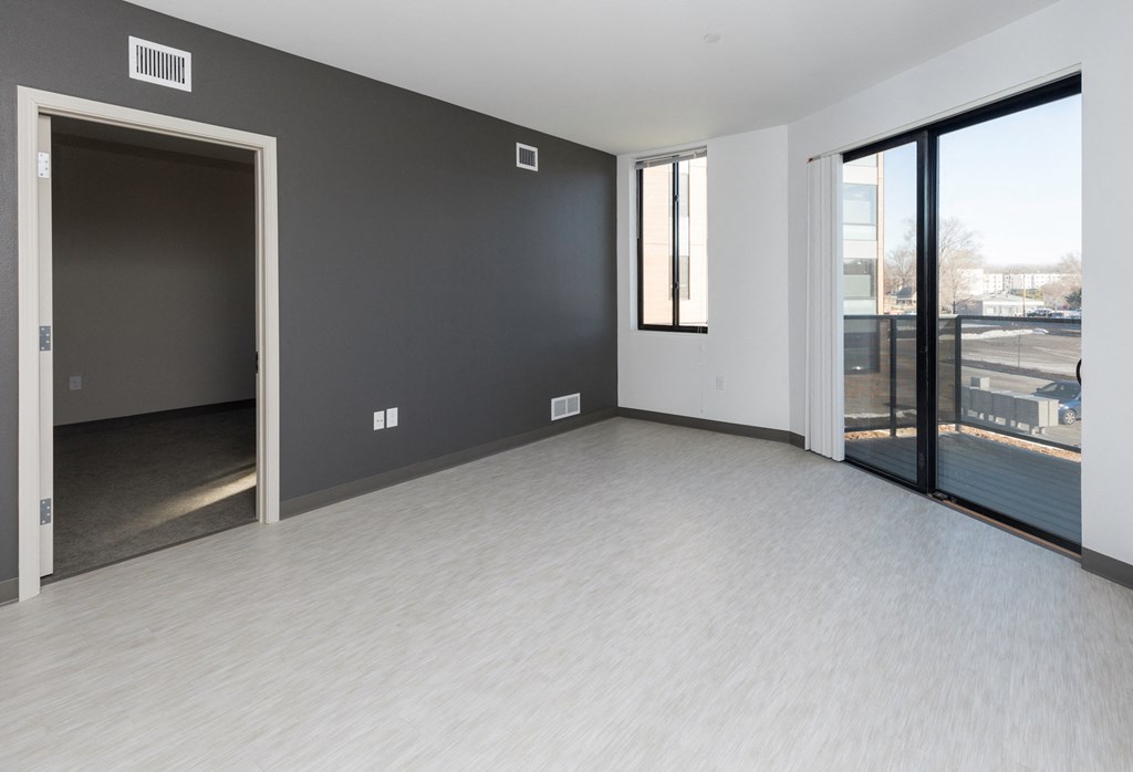an empty living room with large windows and a door to a balcony