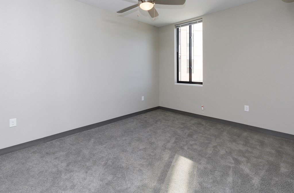an empty room with a ceiling fan and a window