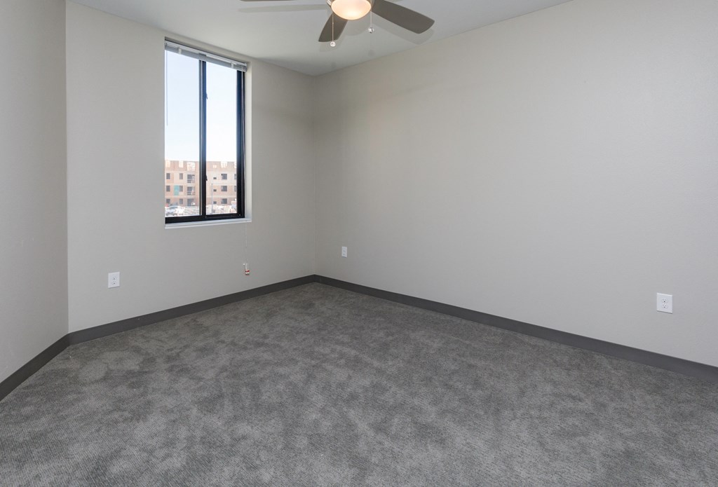 an empty room with a window and a ceiling fan