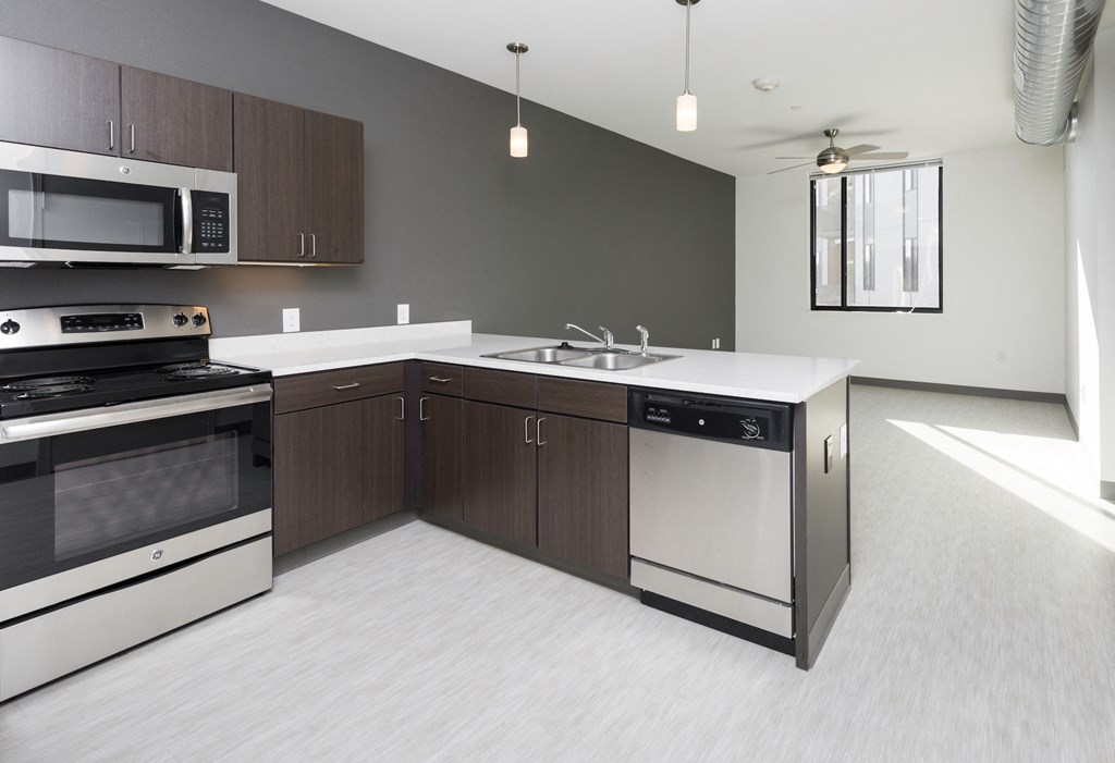 an empty kitchen with stainless steel appliances and wooden cabinets