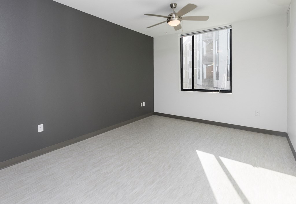 an empty living room with a ceiling fan and a window