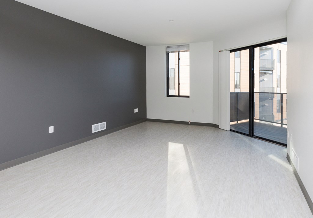 an empty living room with a glass door and a black wall