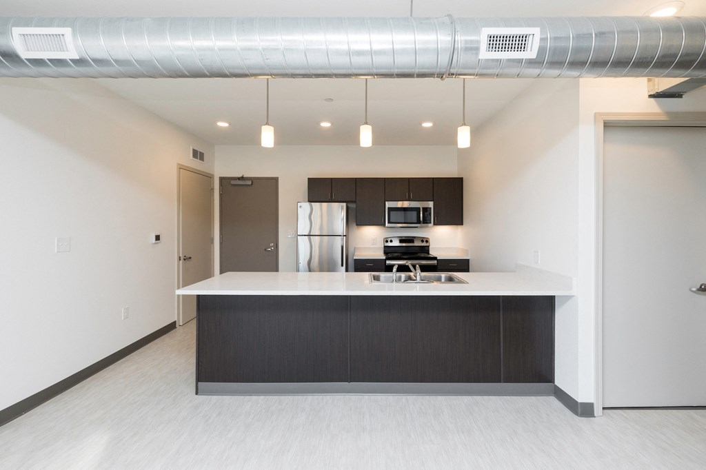 a kitchen with an island and a stainless steel refrigerator
