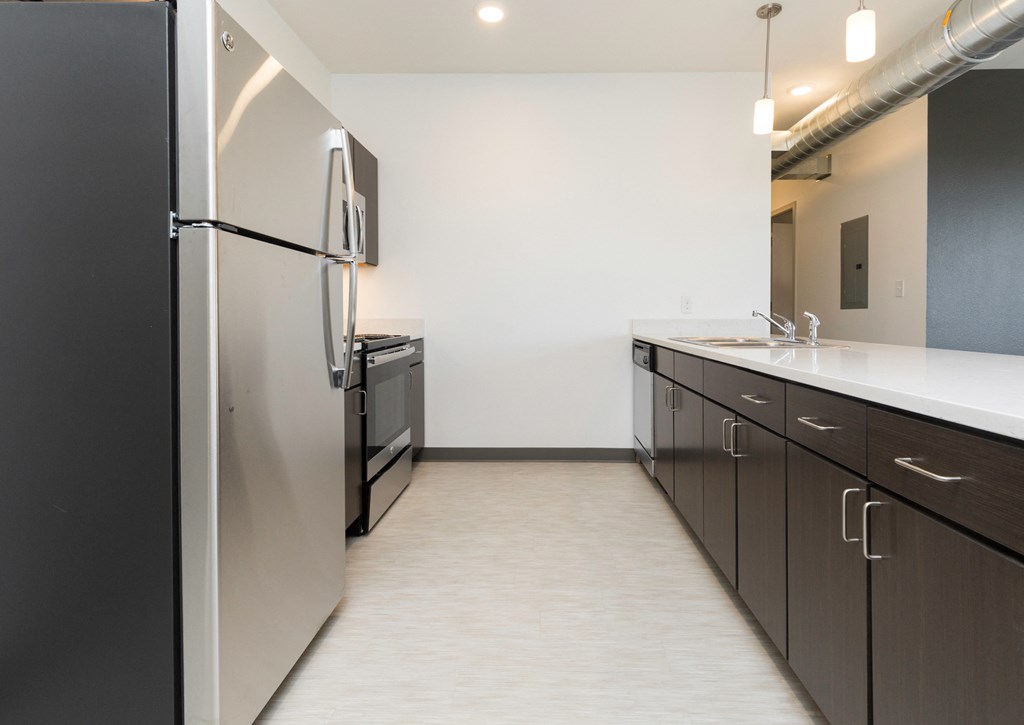 a kitchen with black and white cabinets and a stainless steel refrigerator