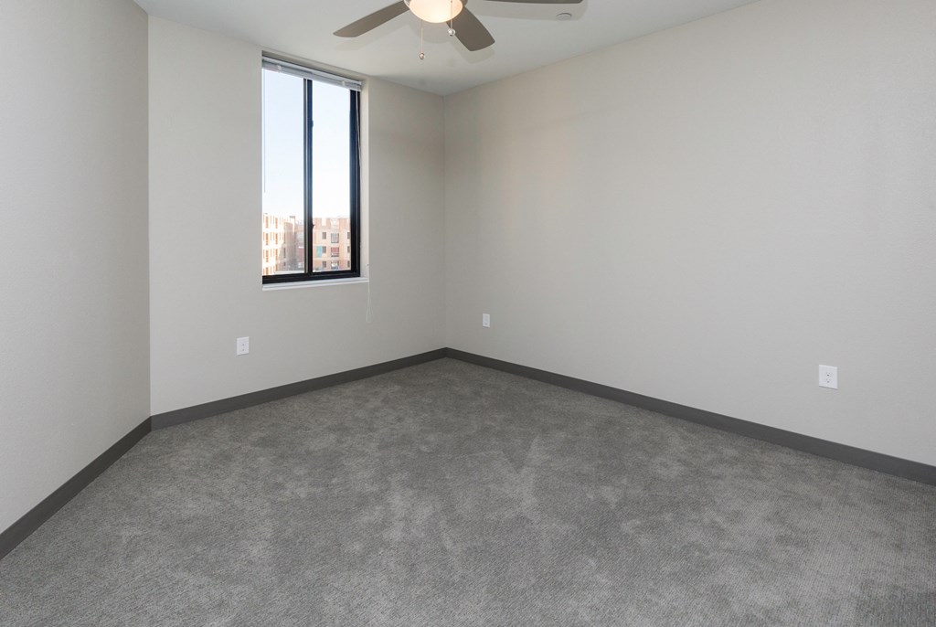 an empty room with a window and a ceiling fan