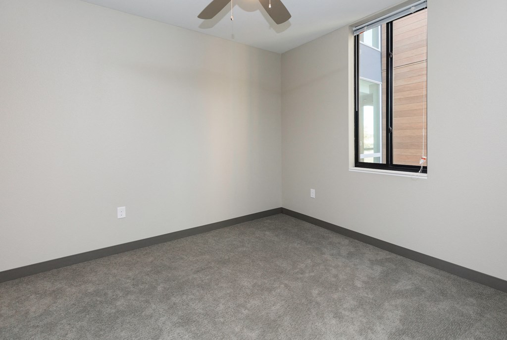 an empty room with a ceiling fan and a window