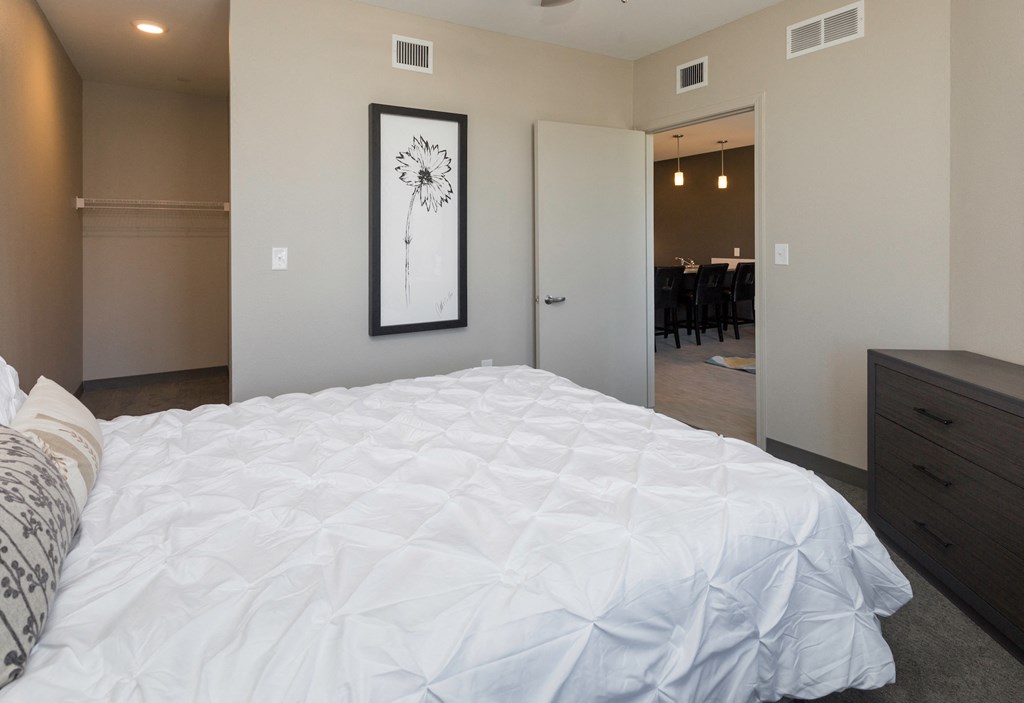 a bedroom with a white bed and a painting on the wall