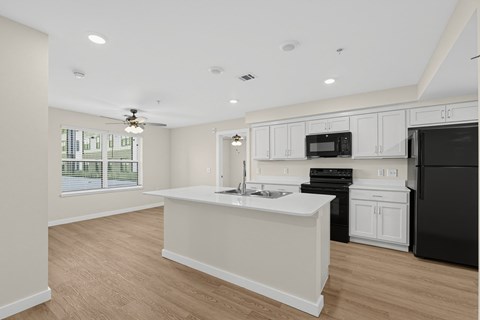 A kitchen with black appliances and white cabinets.